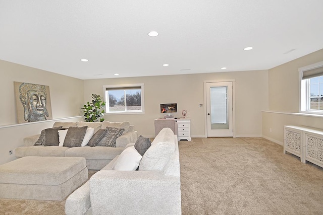 living area featuring baseboards, recessed lighting, and light colored carpet