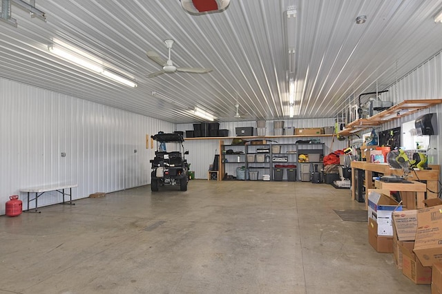 garage featuring ceiling fan, metal wall, and a workshop area