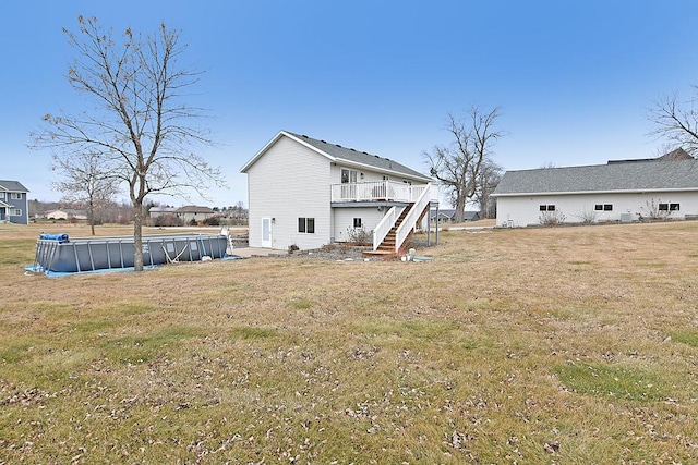 rear view of house featuring stairs, a deck, a lawn, and an outdoor pool