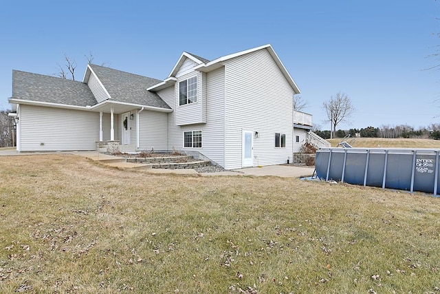 view of front of property with a patio area, a shingled roof, a front yard, and an outdoor pool