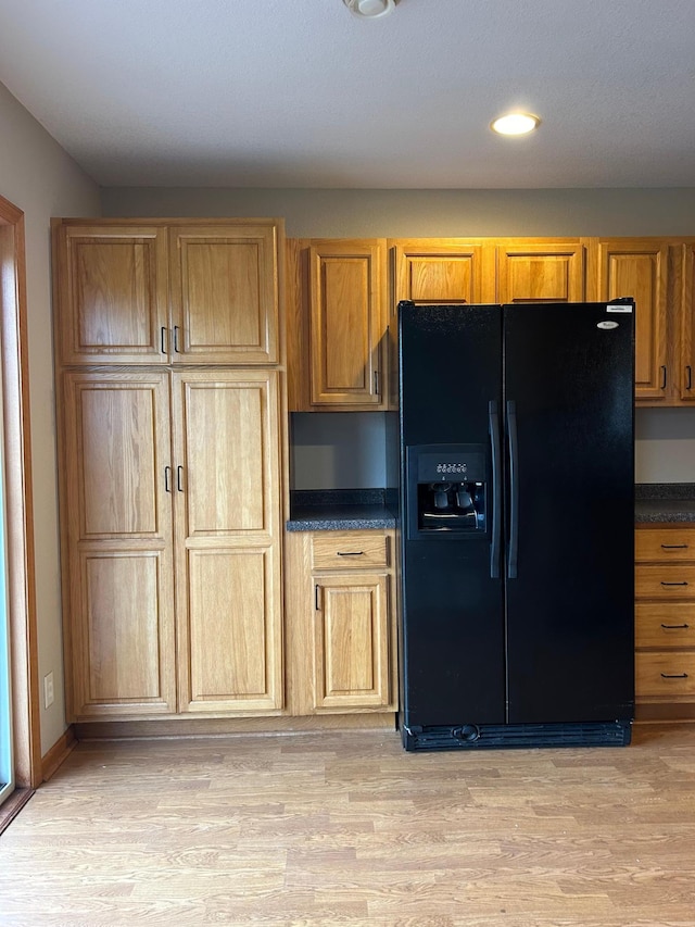 kitchen with built in desk, light hardwood / wood-style floors, and black fridge