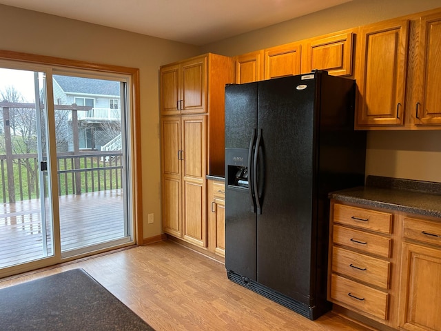 kitchen with light hardwood / wood-style flooring and black fridge