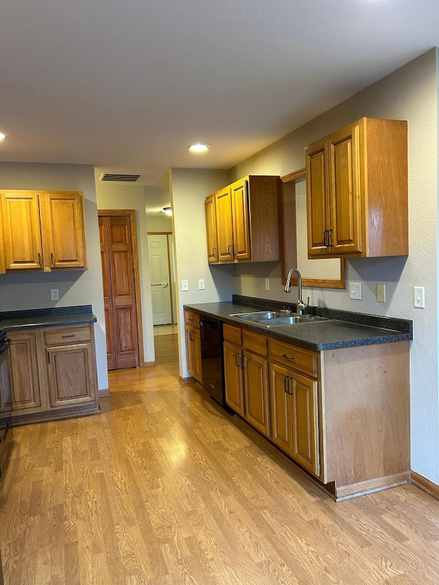 kitchen featuring sink, light wood-type flooring, and black dishwasher