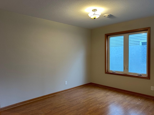 unfurnished room featuring wood-type flooring and a textured ceiling