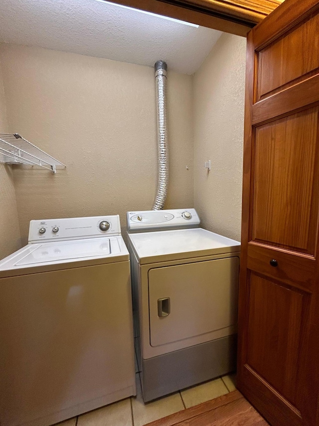 washroom featuring light tile patterned flooring, washer and dryer, and a textured ceiling