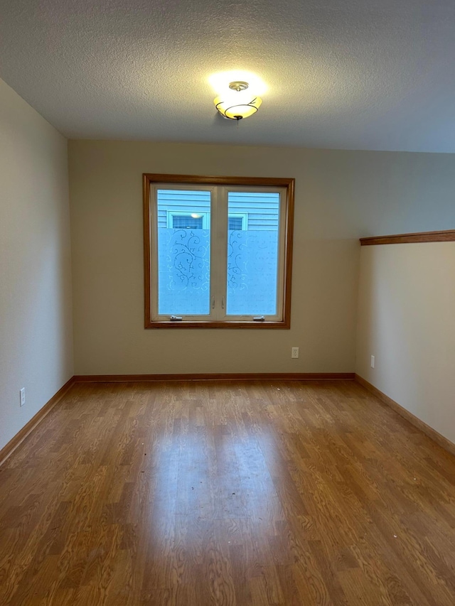 unfurnished room featuring hardwood / wood-style flooring and a textured ceiling