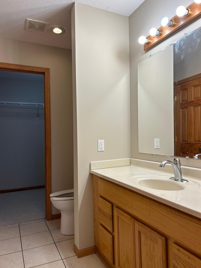 bathroom featuring tile patterned floors, vanity, a textured ceiling, and toilet