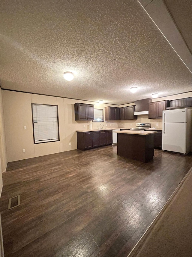 kitchen with a textured ceiling, white fridge, a kitchen island, and dark wood-type flooring