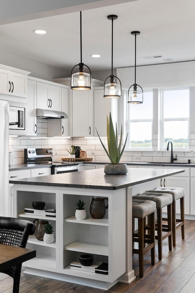 kitchen featuring appliances with stainless steel finishes, white cabinets, dark hardwood / wood-style floors, and a kitchen island