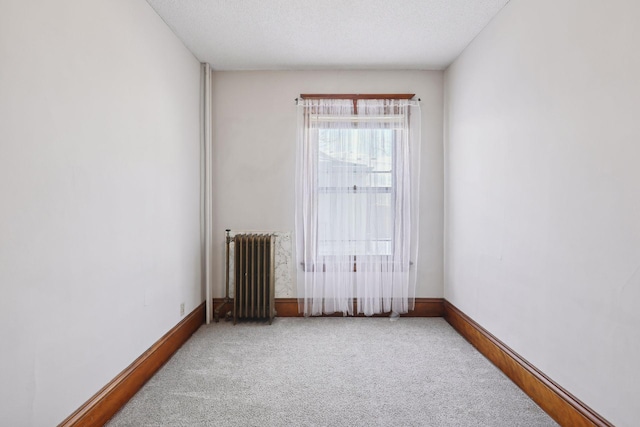 spare room featuring carpet flooring, radiator heating unit, and a textured ceiling