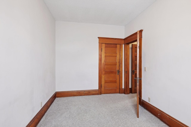 spare room with light colored carpet and a textured ceiling