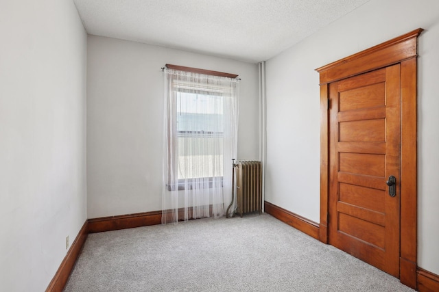 carpeted empty room with radiator heating unit and a textured ceiling