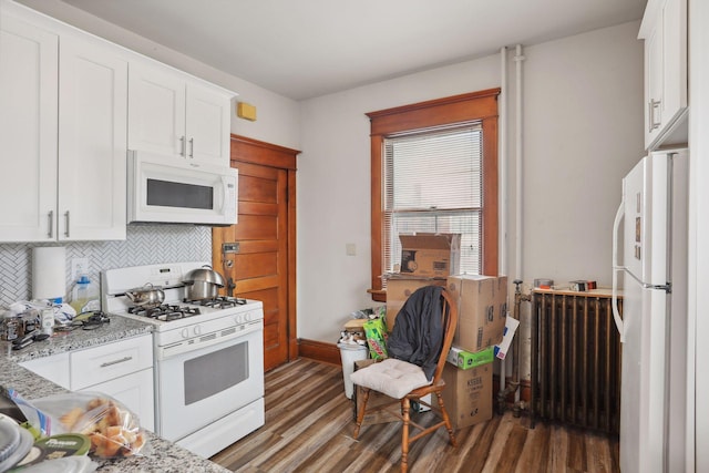 kitchen with radiator, light stone counters, dark hardwood / wood-style flooring, white appliances, and white cabinets