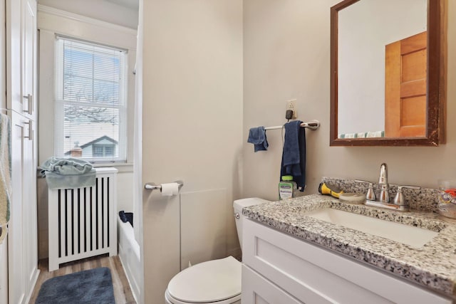 bathroom featuring radiator heating unit, vanity, wood-type flooring, and toilet