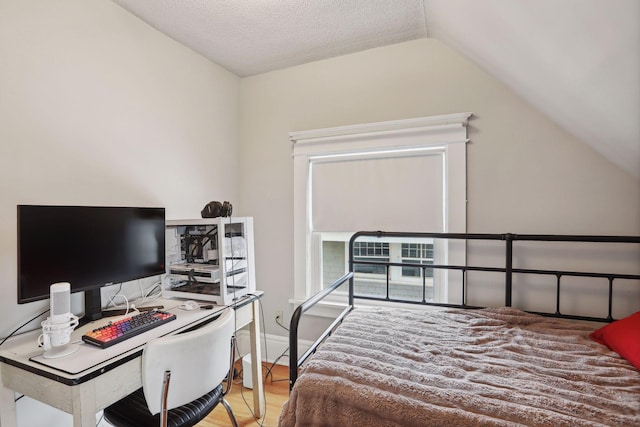 bedroom with a textured ceiling, light hardwood / wood-style flooring, and vaulted ceiling