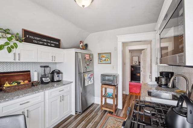 kitchen featuring decorative backsplash, dark hardwood / wood-style flooring, sink, white cabinetry, and stainless steel refrigerator