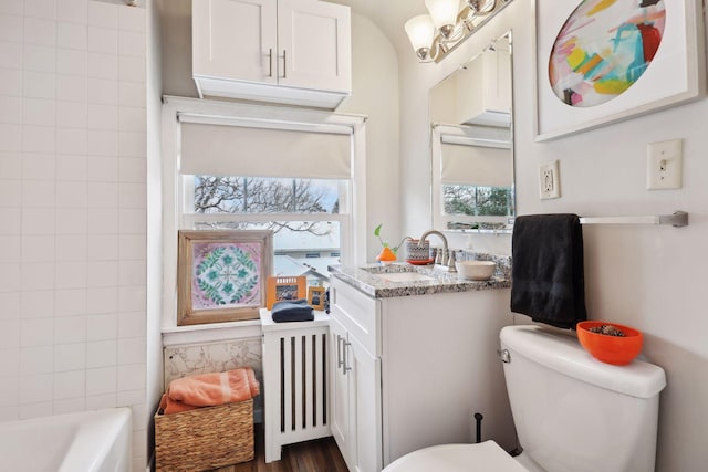 bathroom featuring vanity, hardwood / wood-style flooring, toilet, a tub to relax in, and radiator heating unit