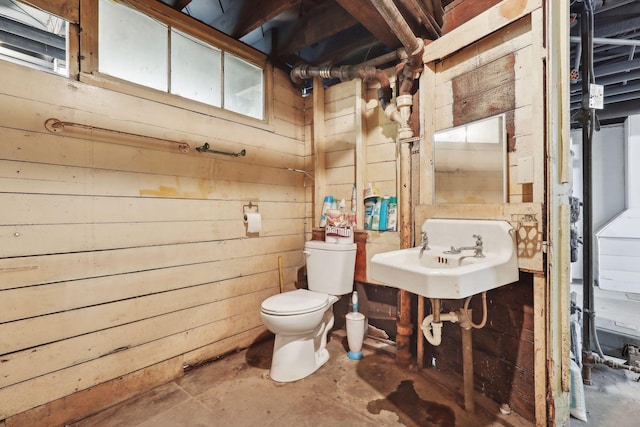 bathroom featuring wood walls, sink, and toilet