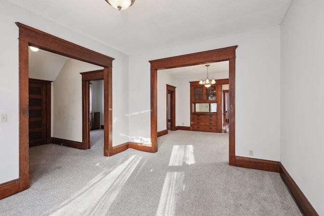 unfurnished room with light colored carpet and a notable chandelier