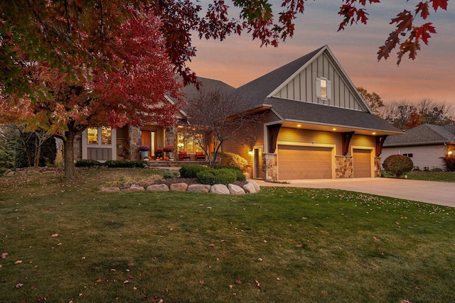 view of front facade featuring board and batten siding, a lawn, a garage, stone siding, and driveway