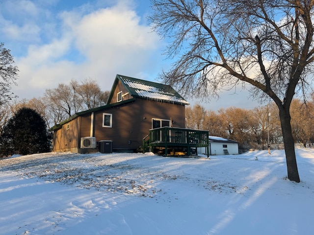 view of snowy exterior with cooling unit and a wooden deck