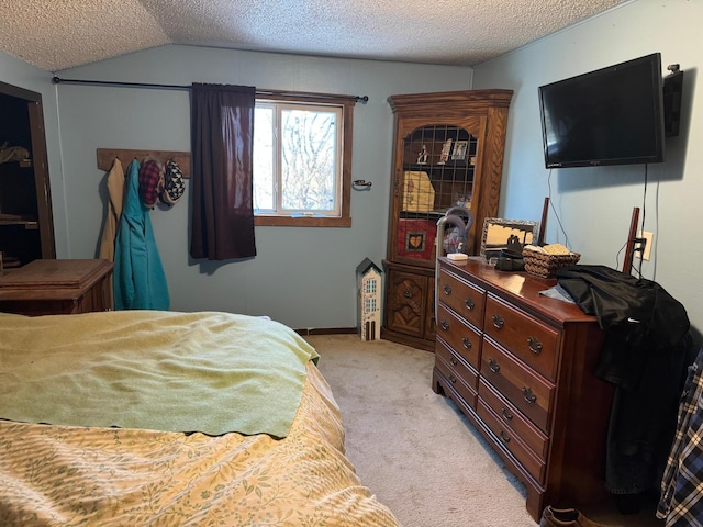 bedroom featuring a textured ceiling, light colored carpet, and lofted ceiling