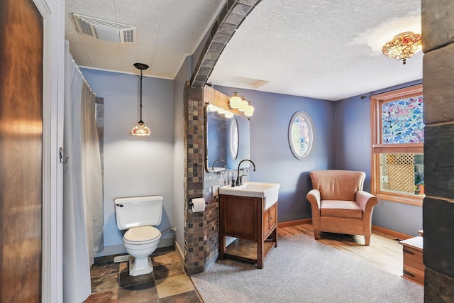 bathroom featuring a textured ceiling, visible vents, baseboards, vanity, and toilet