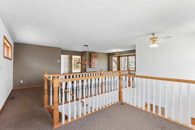 hallway with carpet floors, plenty of natural light, baseboards, and an upstairs landing