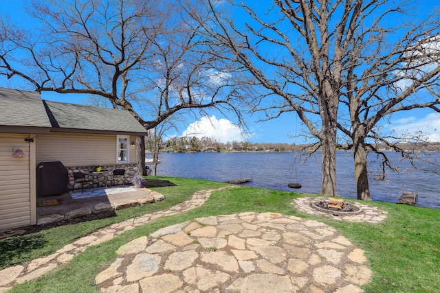view of yard featuring a patio, a water view, and an outdoor fire pit