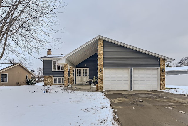 snow covered rear of property featuring a garage