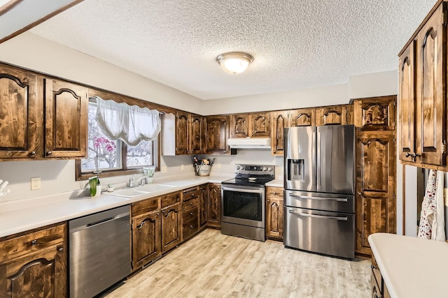 kitchen with a textured ceiling, stainless steel appliances, light hardwood / wood-style flooring, and sink