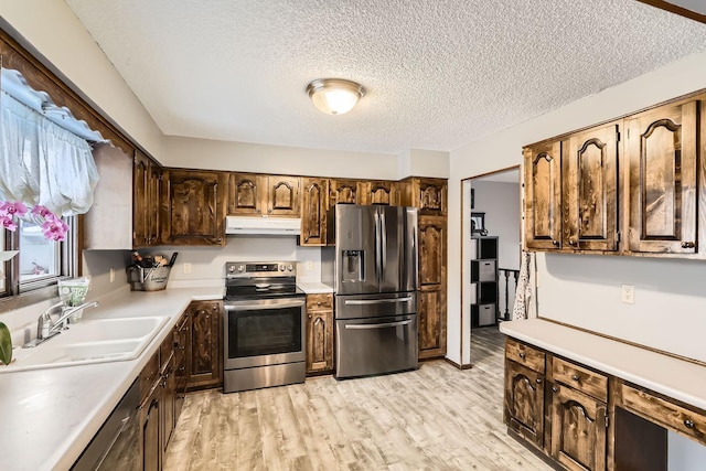 kitchen with a textured ceiling, sink, stainless steel appliances, and light hardwood / wood-style flooring