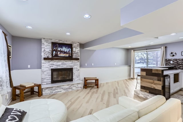 living room featuring a stone fireplace and light hardwood / wood-style floors