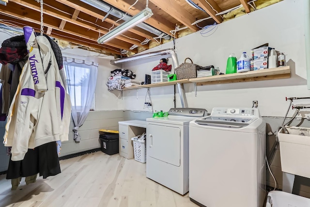 clothes washing area featuring sink, washer and dryer, and light wood-type flooring