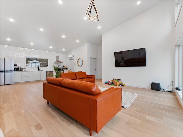 living room with sink, light hardwood / wood-style floors, and a wall mounted air conditioner