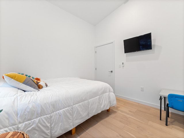 bedroom with light hardwood / wood-style floors and lofted ceiling