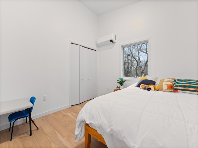 bedroom featuring light hardwood / wood-style floors, a closet, and a wall mounted AC