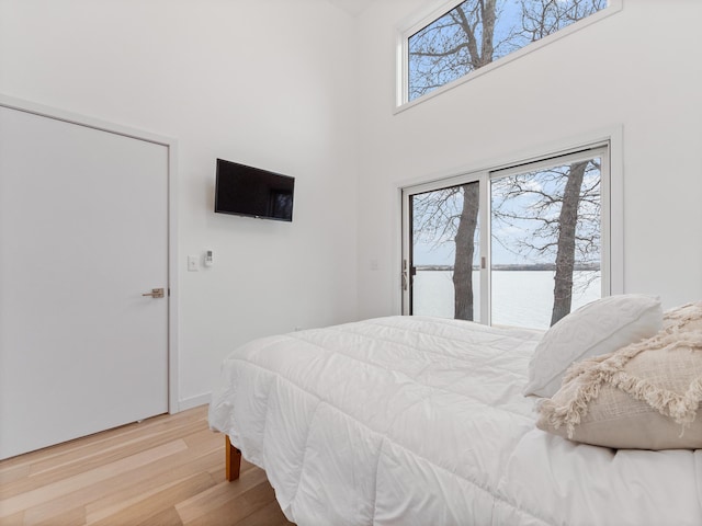 bedroom featuring a high ceiling and light hardwood / wood-style flooring