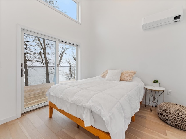 bedroom with multiple windows, hardwood / wood-style floors, and a wall mounted air conditioner