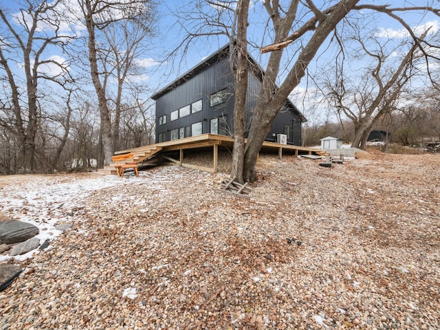 snow covered back of property with a storage shed and a wooden deck