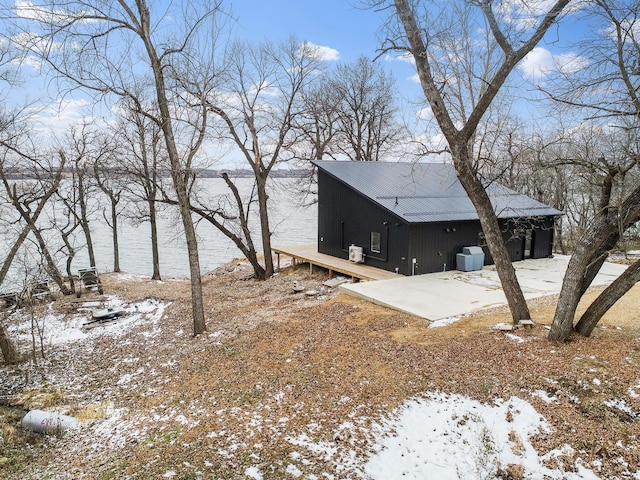 view of snowy exterior featuring a water view and central air condition unit