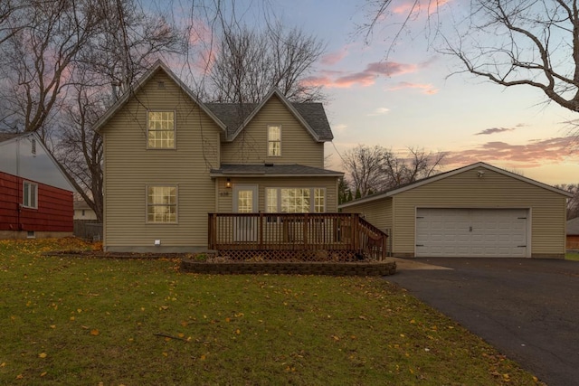 back house at dusk featuring a yard, a garage, and a wooden deck