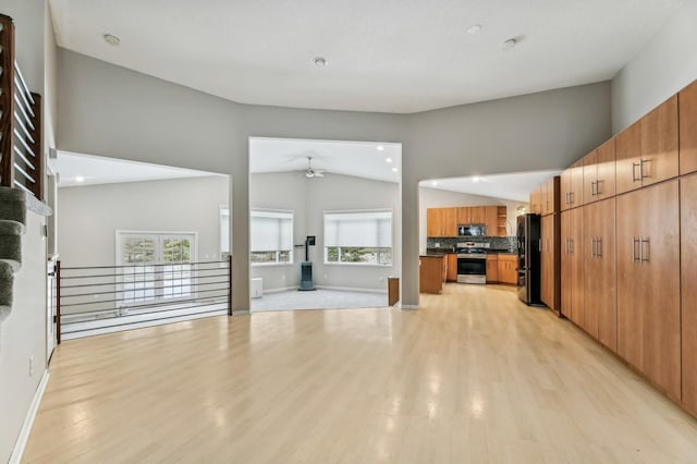 unfurnished living room with ceiling fan, vaulted ceiling, and light hardwood / wood-style flooring