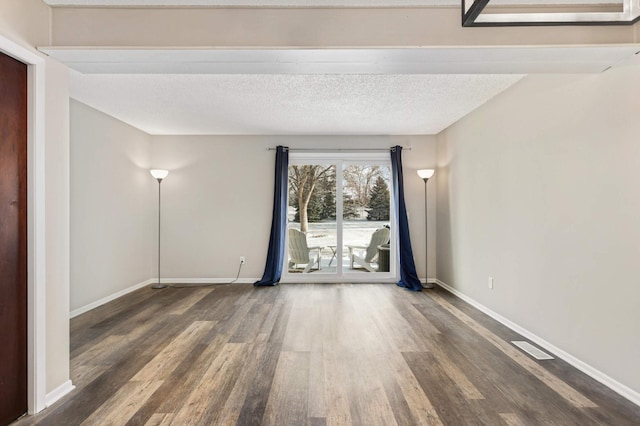 unfurnished room featuring a textured ceiling and dark hardwood / wood-style floors