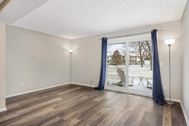 spare room with a textured ceiling and dark hardwood / wood-style flooring