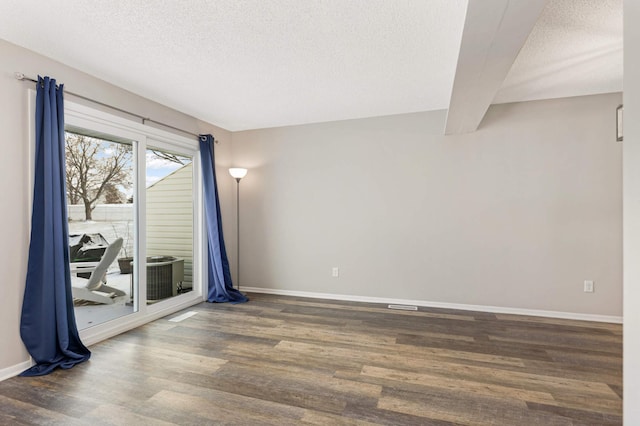 unfurnished room with a textured ceiling, beam ceiling, and dark hardwood / wood-style floors