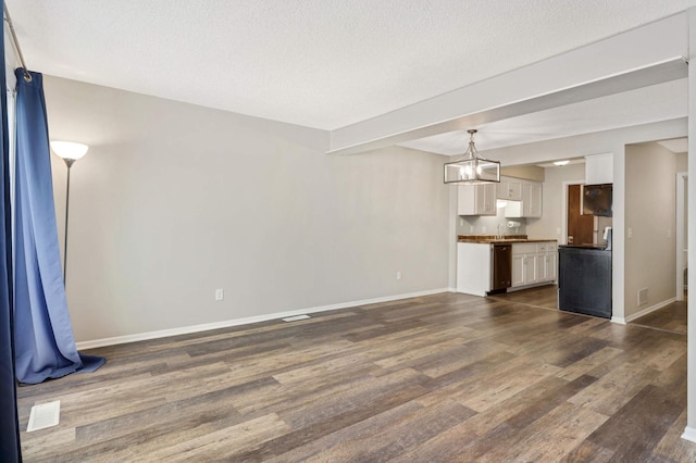 unfurnished living room with dark wood-type flooring and a textured ceiling