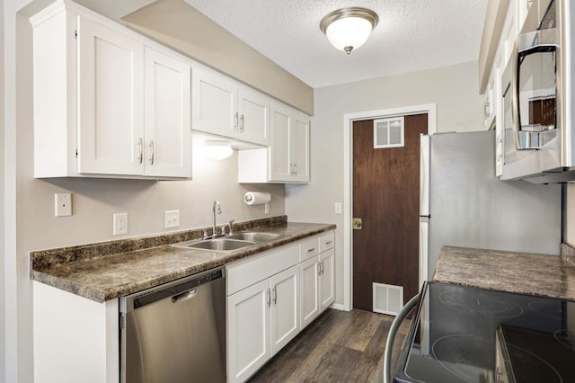 kitchen with dark wood-type flooring, appliances with stainless steel finishes, white cabinets, and sink