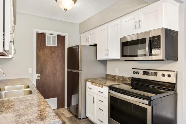 kitchen featuring a textured ceiling, stainless steel appliances, white cabinets, and sink