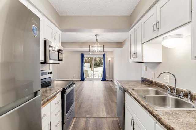 kitchen featuring appliances with stainless steel finishes, dark hardwood / wood-style floors, a textured ceiling, white cabinets, and sink